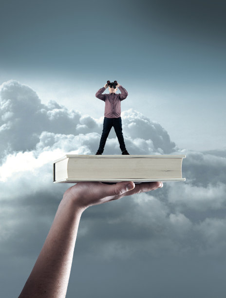 在一本书上看望远镜的年轻人。图片下载