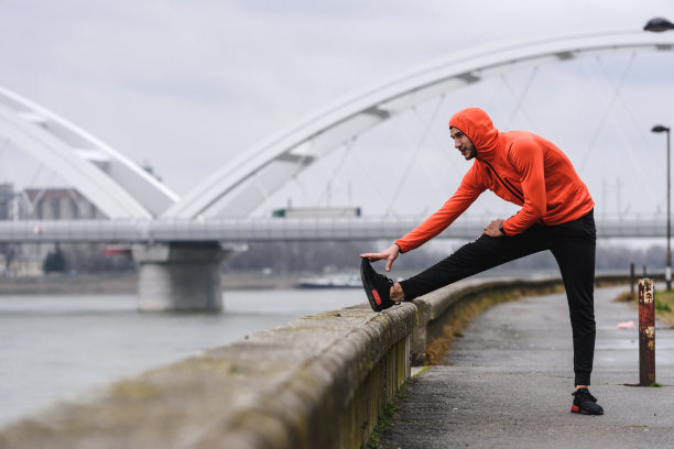 英俊的年轻运动员在一个阴天跑步前伸展他的肌肉图片下载