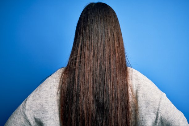 年轻美丽的亚洲女人穿着休闲毛衣站在蓝色孤立的背景站向后看远离与手臂上的身体图片下载