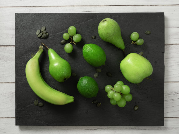 水果背景绿色的颜色组成在深色的石板和白色的木桌。夏季抽象创意时尚新鲜健康理念。平放俯视图图片下载