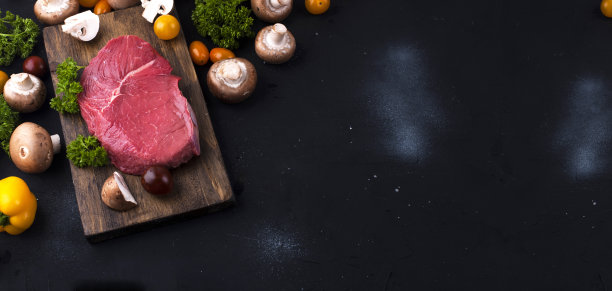 牛肉。红肉，各种蔬菜，放在黑色的石桌上烹饪。旗帜长格式。副本的空间。图片下载