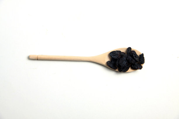 黑葡萄干放在木勺上平躺着图片下载