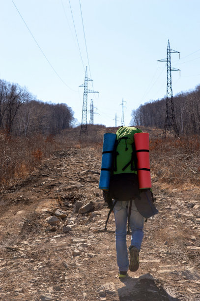 早春的一天，一个年轻人拿着两张彩色的旅游地毯爬上了树图片下载