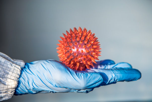 在实验室里拿着红色冠状病毒模型的医生，分子COVID19素材图片
