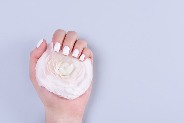 女人的手戴着婚戒，修过指甲，白色蕾丝点缀着小花图片下载