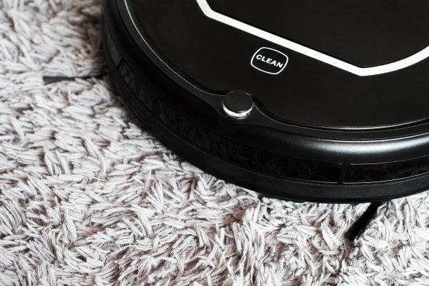 用自动吸尘器清洁蓬松的地毯。地板机器人真空吸尘器，客厅智能机器人自动无线清洁技术机器。图片下载