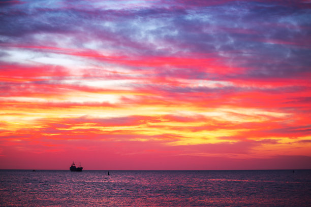 夕阳西下，海面上有帆船，风景优美图片下载