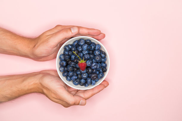 手里拿着蓝莓。手里拿着蓝莓放在彩色的背景上。写的地方。从以上观点。图片下载