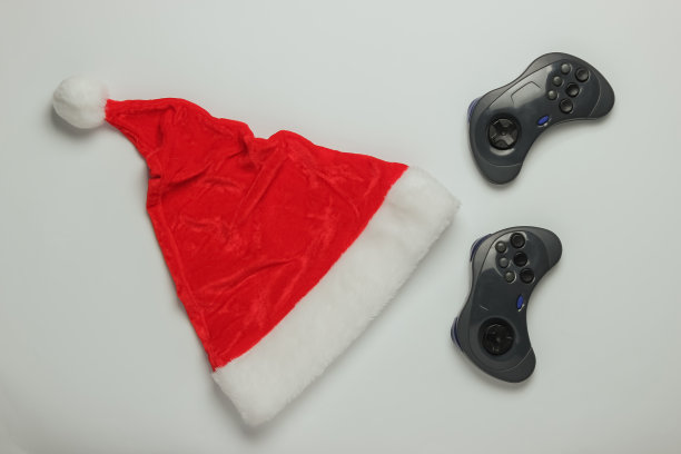 圣诞老人帽和游戏手柄在白色背景。玩家的概念。圣诞假期。俯视图图片下载