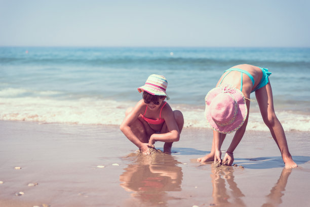 孩子们在海滩上玩贝壳图片下载