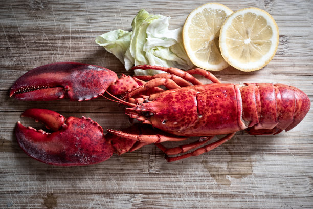 红龙虾配蔬菜和柠檬木切板背景，俯视图/龙虾晚餐图片下载