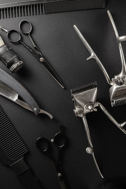 黑色的表面是旧的理发工具。两个老式手动理发器，梳子，剃须刀，剃须刷，美发剪刀。黑色的单色。垂直方向。前视图。图片下载