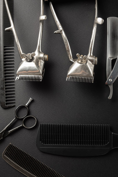 黑色的表面上是旧的理发师工具。两个老式的手持理发器，梳子，剃须刀，美发剪刀，剃须刷。黑色的单色。垂直方向。图片下载