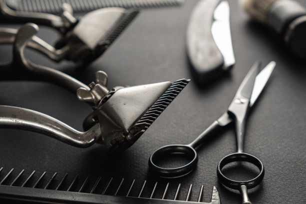 黑色的表面是旧的理发工具。两个老式手动理发器，梳子，剃须刀，剃须刷，美发剪刀。黑色的单色。垂直图片下载