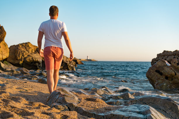 日落时分，男人在马托西纽什探索岩石和沙滩图片下载