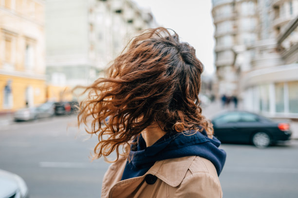 特写：身穿米色外套的卷发年轻女子图片下载