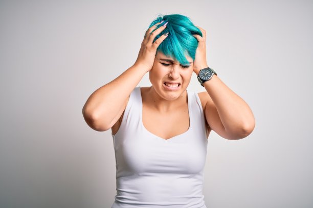 年轻美丽的女人与蓝色时尚的头发穿休闲t恤在白色的背景遭受头痛绝望和压力，因为疼痛和偏头痛。手放在头上。图片下载