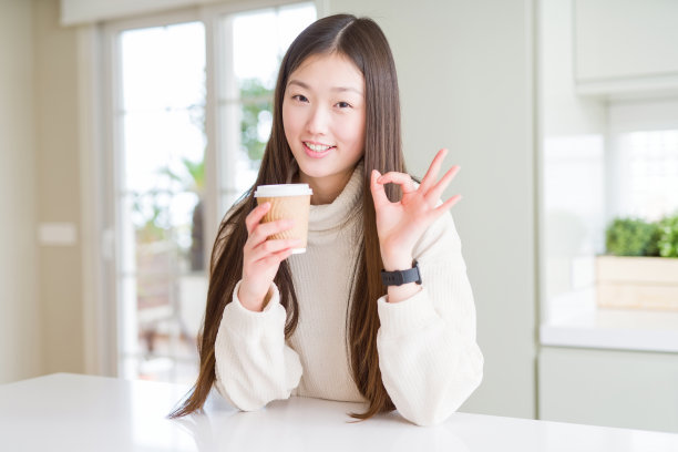 拿着外卖纸杯喝咖啡，做OK手势的漂亮亚裔女性图片下载