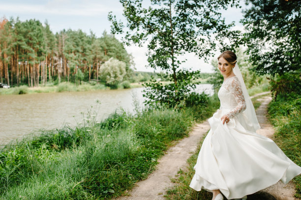 肖像迷人的新娘穿着婚纱。新娘在森林里奔跑。自然,国家。图片下载