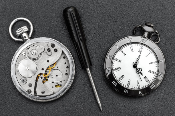 坏了的怀表和新的怀表与螺丝刀在黑色背景。发条。图片下载
