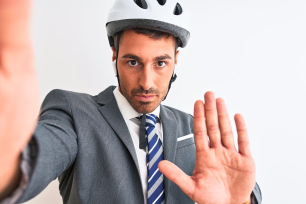 年轻英俊的商人戴着自行车头盔自拍在孤立的背景与开放的手做停止标志与严肃和自信的表情，防御手势图片下载