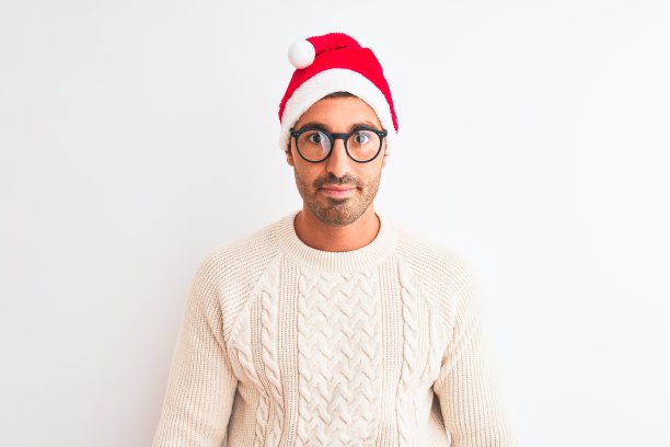 年轻英俊的男子戴着圣诞帽和眼镜在孤立的背景与严肃的表情在脸上。简单自然的看相机。图片下载