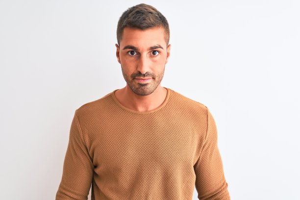 年轻英俊优雅的男子穿着冬季毛衣在孤立的背景与严肃的表情在脸上。简单自然的看相机。图片下载