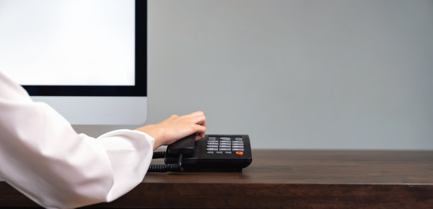 一个女人在办公桌上拿着电话和电脑。图片下载