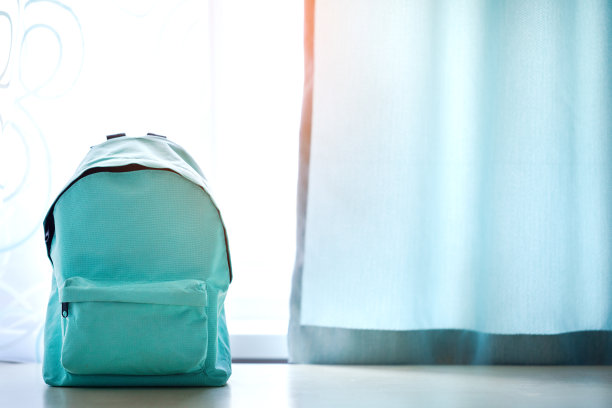 蓝色的书包放在孩子们房间的桌子上。图片下载