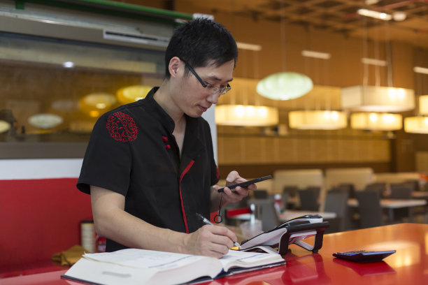 在中国餐馆入口处柜台查看手机的中国男人图片下载