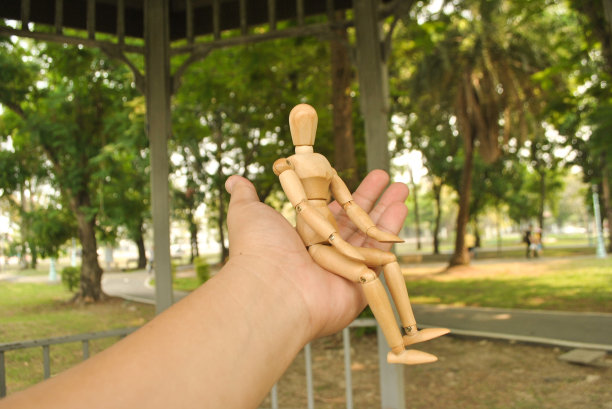 亚洲人左手边的木制人形，以自然为背景图片下载