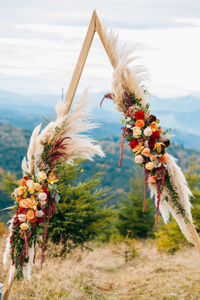三角木拱门由蒲草、大丽花和玫瑰组成。装饰花艺图片下载