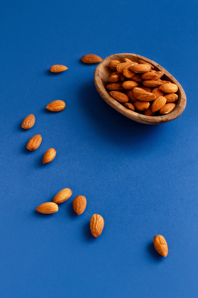 蓝色背景的碗里的新鲜杏仁图片下载