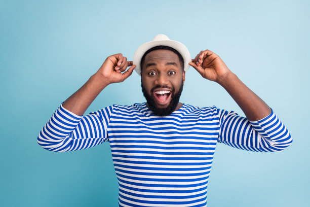 疯狂的深色皮肤的家伙的照片，旅行者休息国外度过空闲时间，阳光度假，看低购物中心的价格，穿白色的太阳帽条纹水手衬衫孤立的蓝色背景图片下载