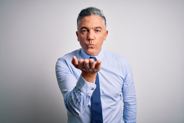 穿着优雅衬衫和领带的英俊灰发中年商务男士对着镜头飞吻，表达爱意图片下载