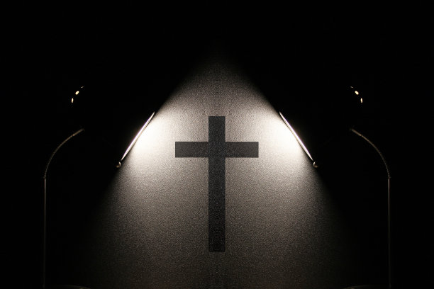 灯光照在墙上一个天主教十字架的剪影上。宗教。图片下载