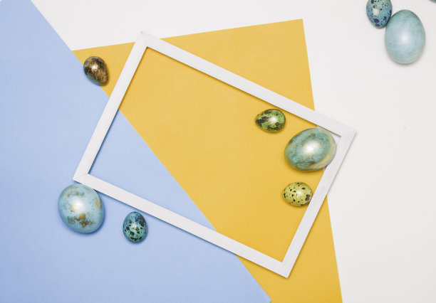 彩色的复活节彩蛋围绕一个木制的白色框架在白色，黄色和蓝色的背景。复活节快乐!图片下载