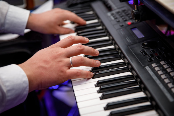 一个男人在玩电子合成器。手指在键盘上。图片下载