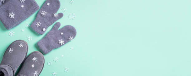 冬天暖和的衣服平躺着。羊毛女装毛衣，围巾，靴子，蓝色背景的雪花。俯视图，复制空间。横幅图片下载