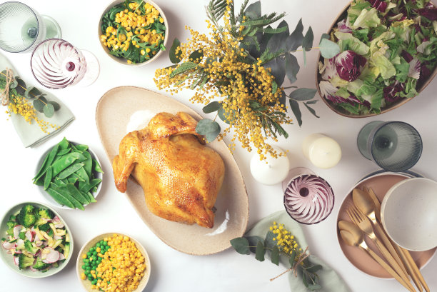 情人节，妇女节，母亲节，婚礼早午餐，节日家庭午餐和晚餐的概念。节日家庭餐桌。盛有沙拉和蔬菜的盘子，碗，小吃，烤鸡，桉树，含苞欲放的花图片下载