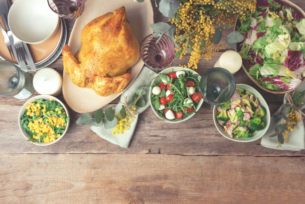 情人节，妇女节，母亲节，婚礼早午餐，节日家庭午餐和晚餐的概念。节日家庭餐桌。盛有沙拉和蔬菜的盘子，碗，小吃，烤鸡，桉树，含苞欲放的花图片下载