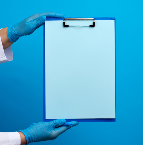 女医生的手在蓝色医用乳胶手套持有一个文件夹与曲别针图片下载