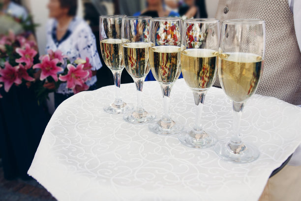 在豪华餐厅婚宴上，优雅着装的侍者端着盛有香槟的玻璃杯图片下载
