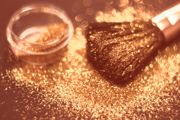 化妆刷和设计上的金色闪光纹理。在白色背景上。选择性聚焦-图像图片下载