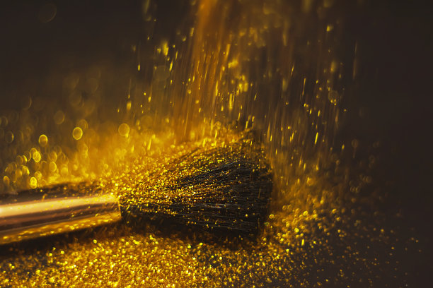 化妆刷和设计上的金色闪光纹理。在白色背景上。选择性聚焦-图像图片下载