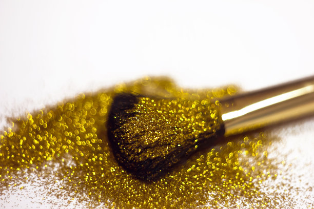 化妆刷和设计上的金色闪光纹理。在白色背景上。选择性聚焦-图像图片下载