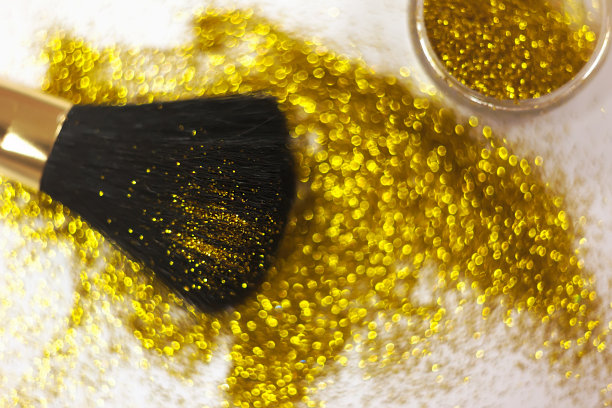 化妆刷和设计上的金色闪光纹理。在白色背景上。选择性聚焦-图像图片下载