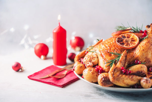 带有节日装饰、蜡烛、光晕的完整烤鸡，混凝土背景。复制空间。朋友或家庭晚餐。节日圣诞餐桌。传统的感恩节或朋友节假日庆祝菜肴图片下载