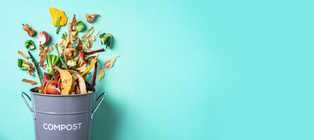 在蓝色背景的白色堆肥箱里去皮的蔬菜。蓝色背景上的垃圾桶，用来堆放厨房里的剩菜。前视图。回收陡坡”概念。可持续和零浪费的生活方式。图片下载