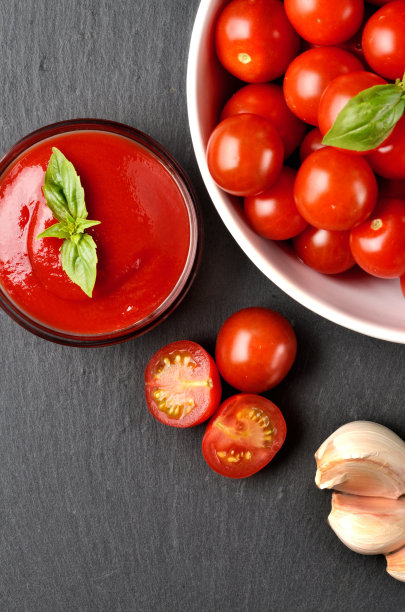 特写自制番茄酱，由新鲜的樱桃番茄，大蒜，罗勒在黑色石板。前视图。垂直的照片。图片下载
